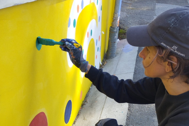 L'artista Carol Rolla lavora al murales in via Risorgimento